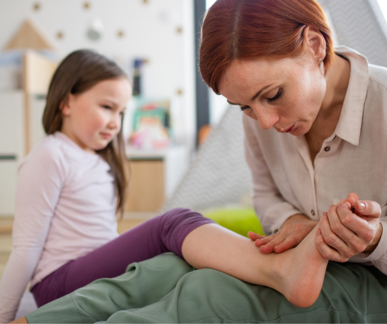 woman holding childs foot and inspecting the ankle