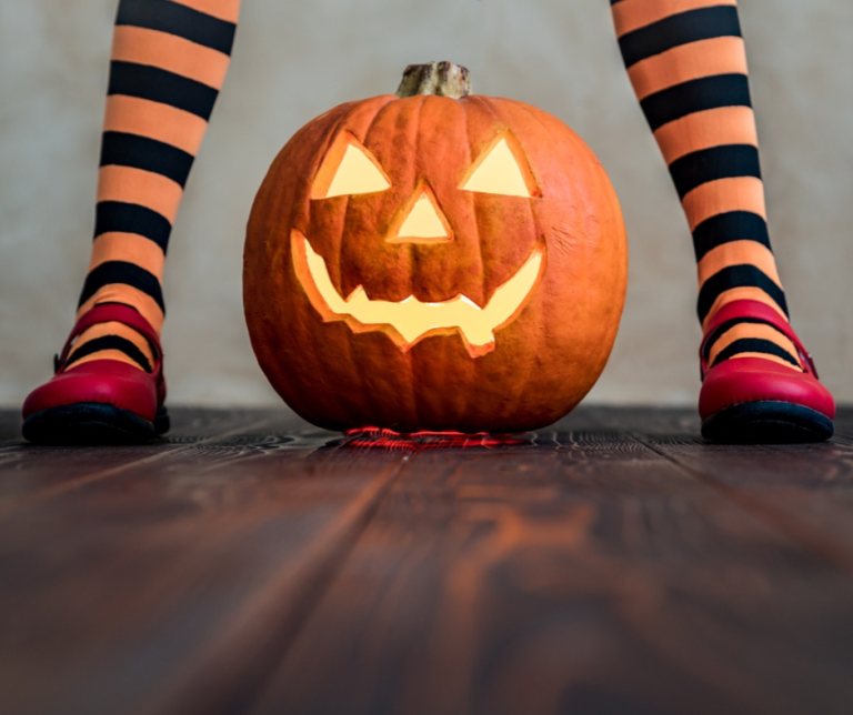 Home 28 person with orange and black stockings standing over a carved pumpkin